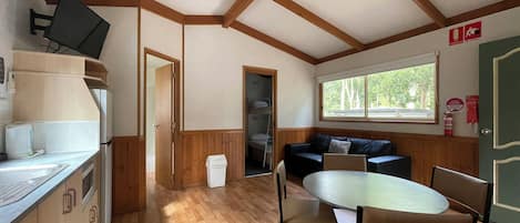 A cozy cabin-style room with a kitchen, dining area, and a large window.