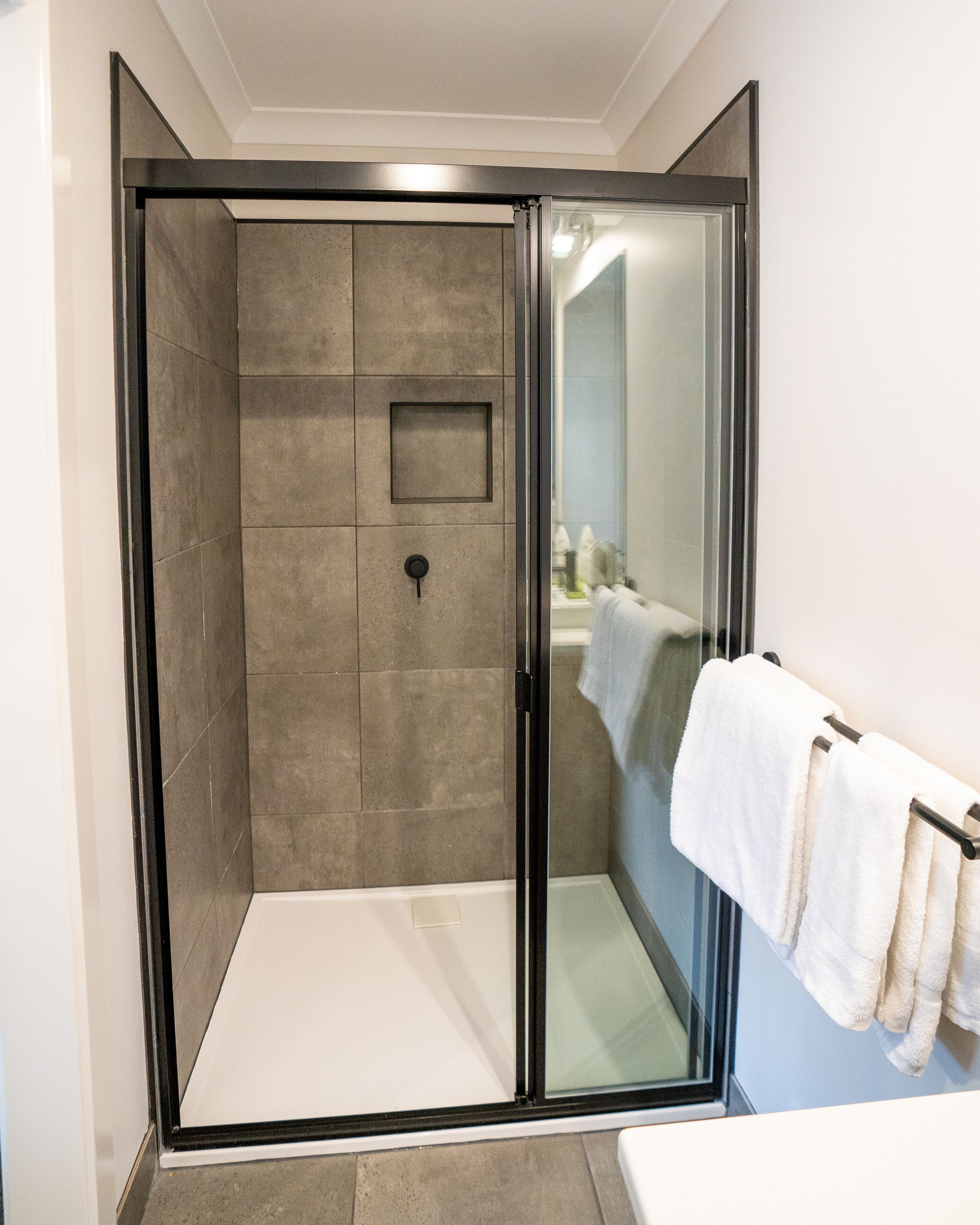 A walk-in shower with a glass door, tiled walls, and a towel rack with towels.