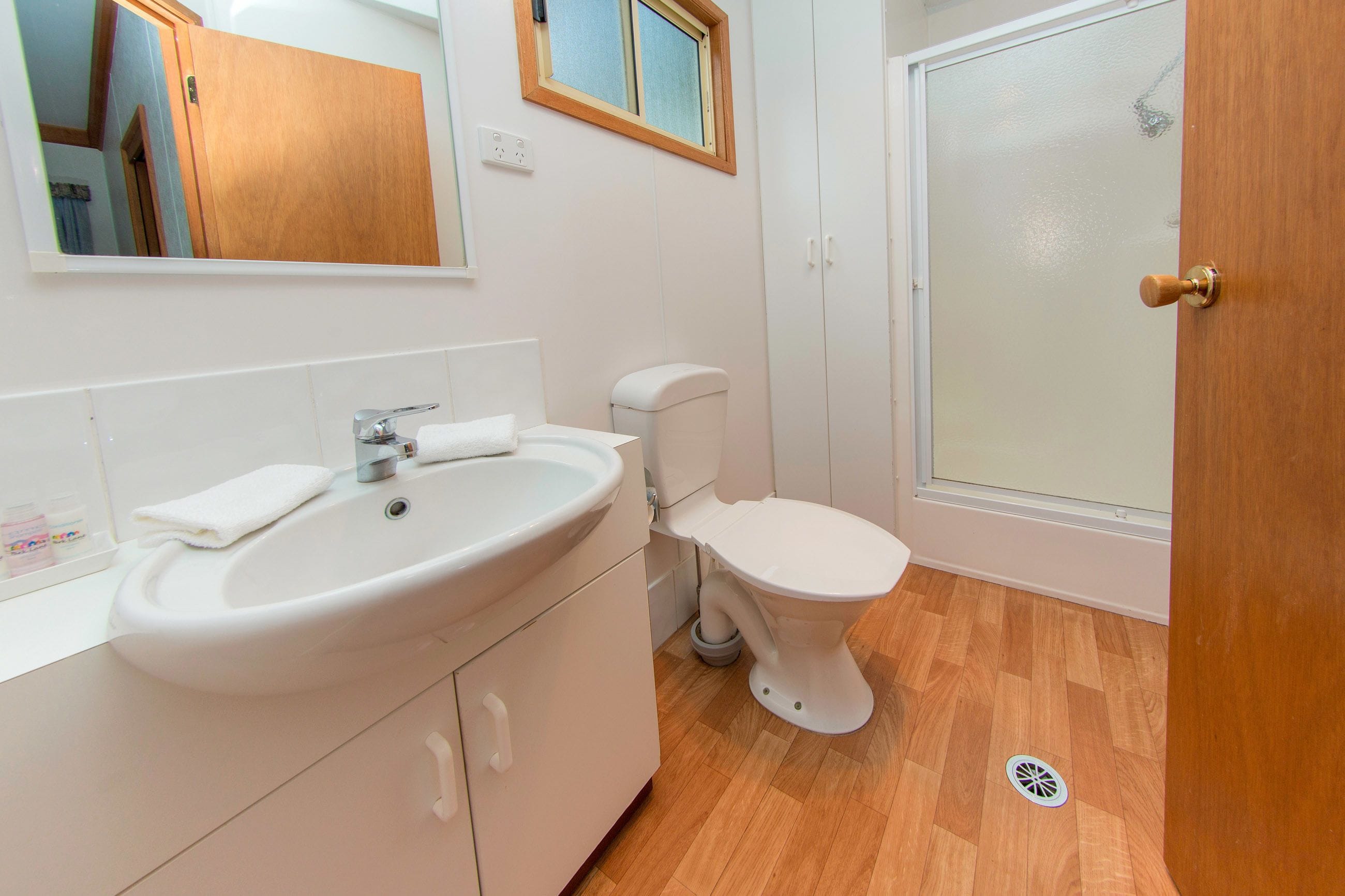 A bathroom with a white sink, toilet, and a shower area.