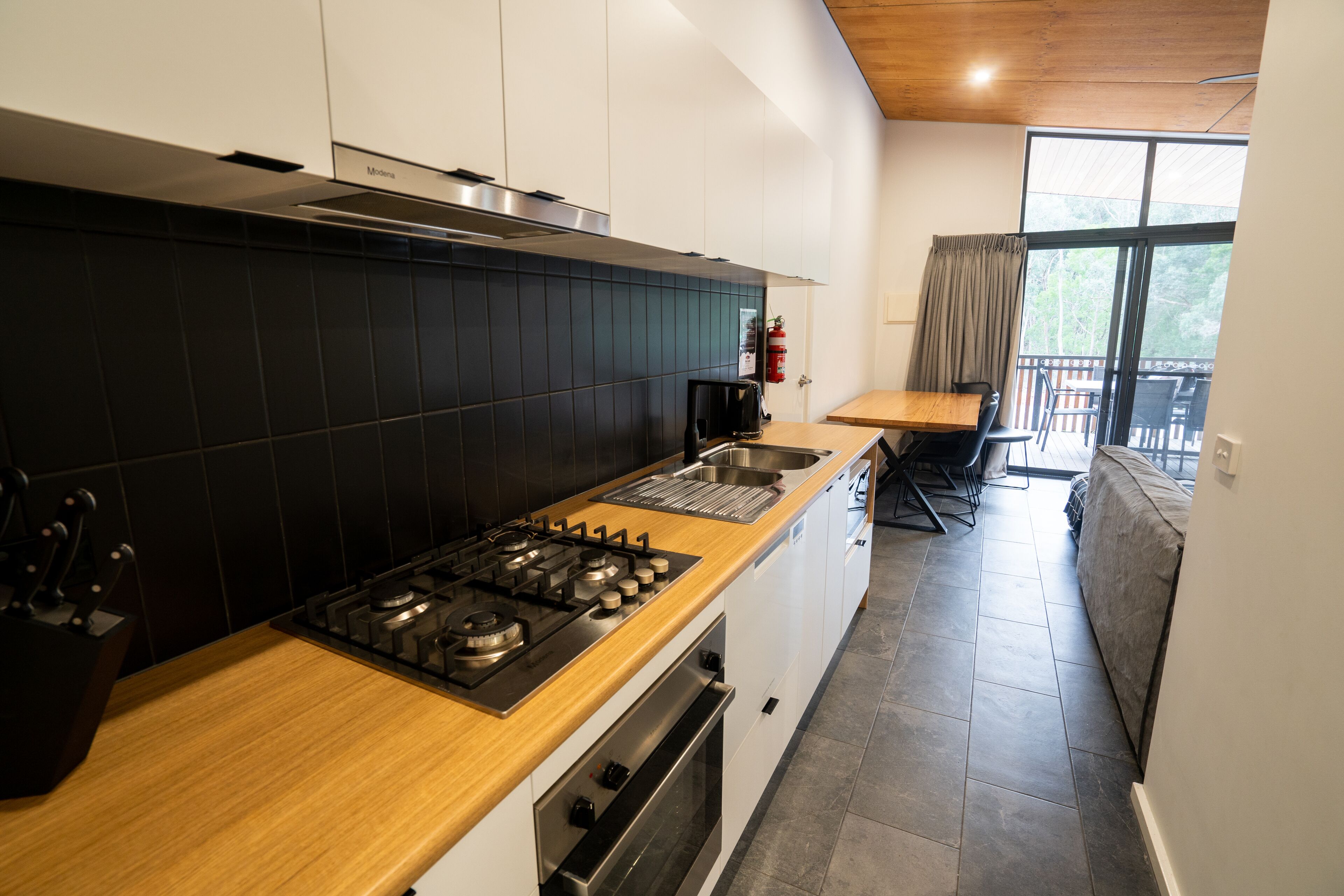 Une cuisine moderne équipée d’une cuisinière à gaz, d’un four encastré et d’un plan de travail en bois.