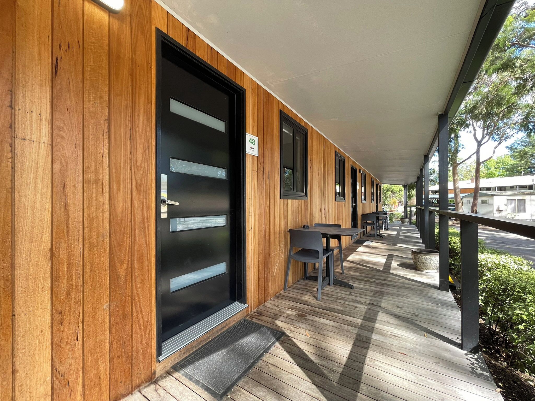 Un espacio al aire libre cubierto con paredes de madera y una puerta negra con el número 48.