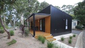 Un edificio moderno de dos pisos con un espacio exterior cubierto y una terraza de madera.