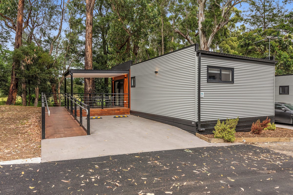 A modern, single-story mobile home with a covered porch and a small deck.