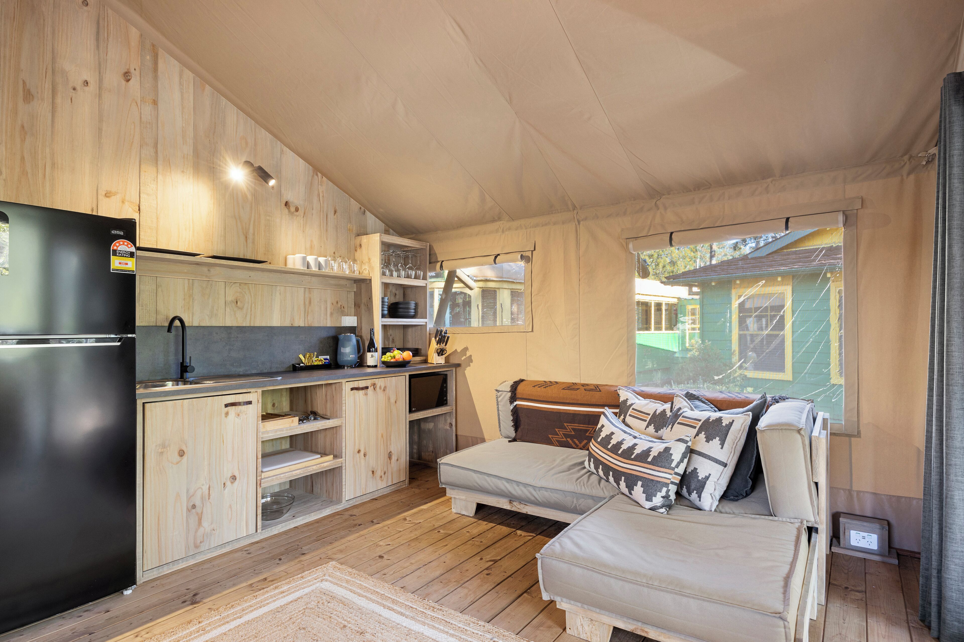 A compact kitchen with wooden cabinets, a refrigerator, and a dining area with a bench.