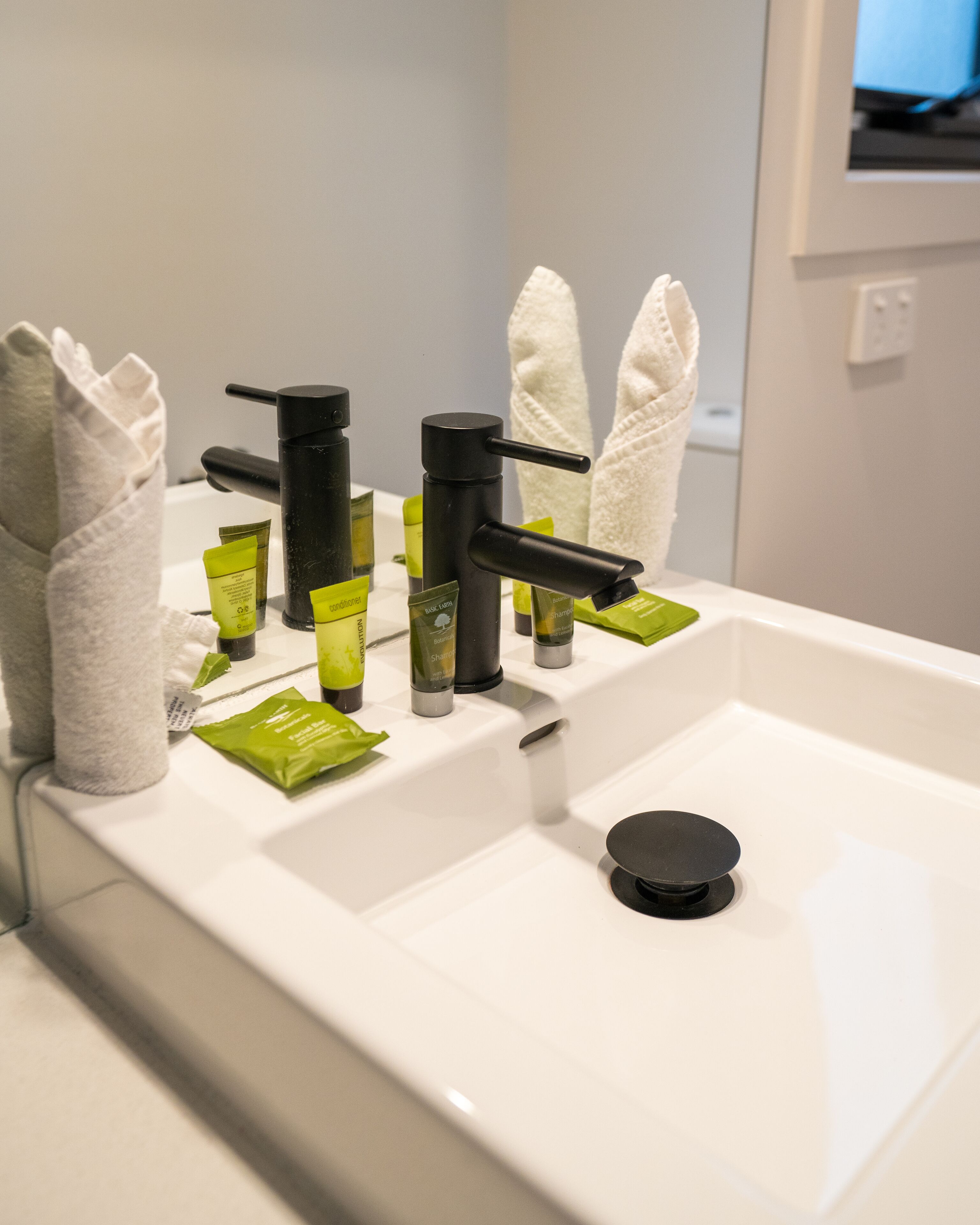 Un lavabo dans la salle de bain, avec des articles de toilette, un porte-serviettes et un miroir.