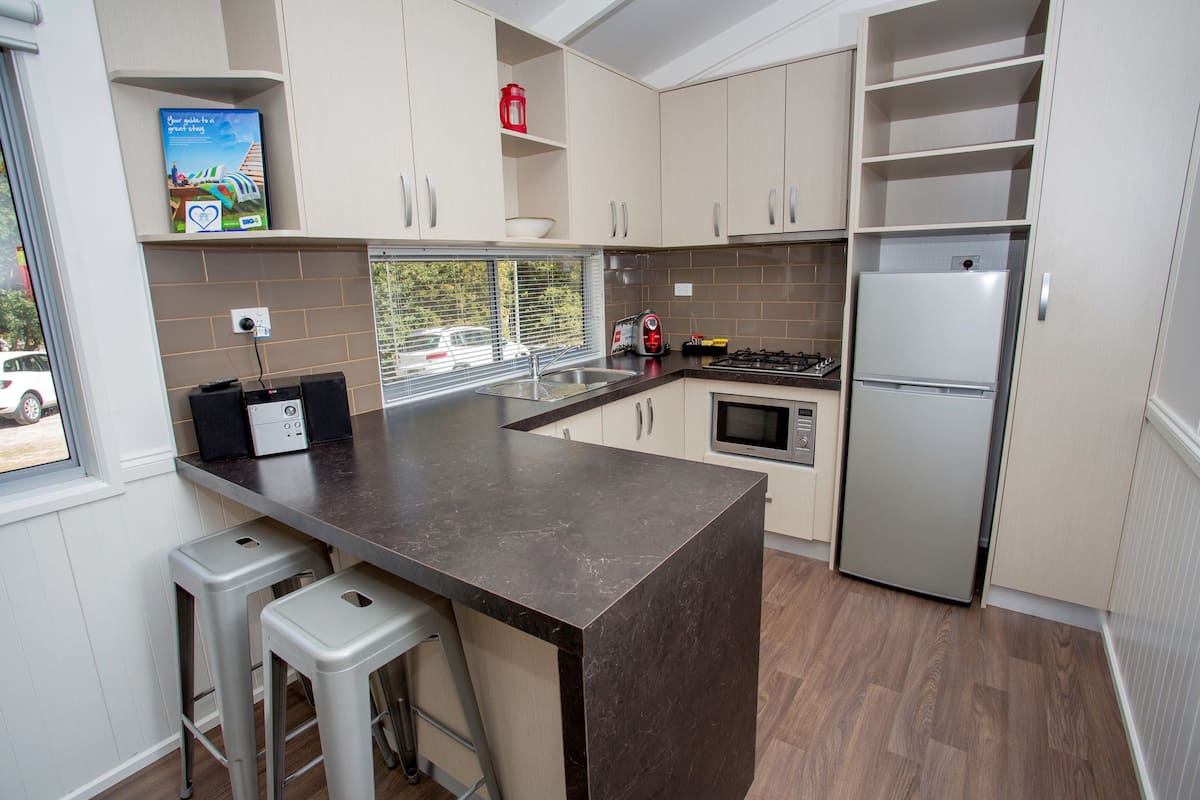 A modern kitchen with a central island, stainless steel appliances, and light wood flooring.