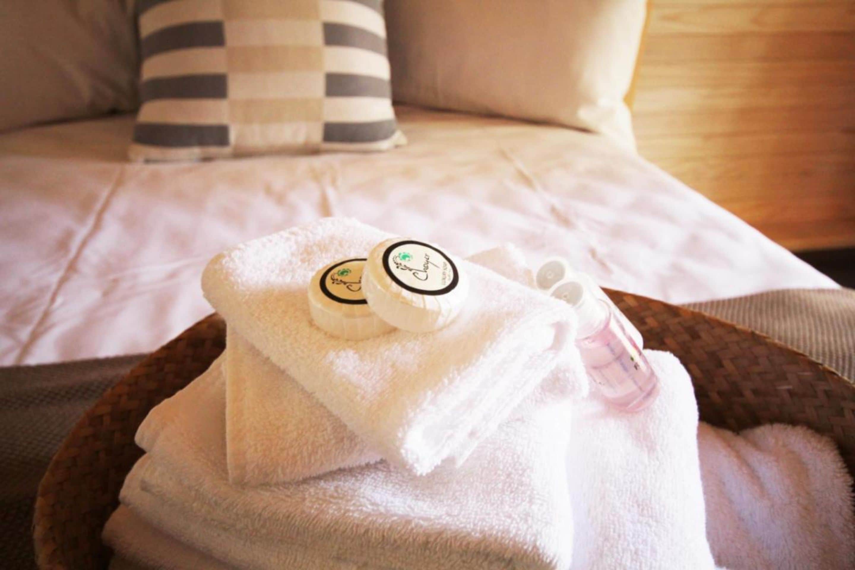 A neatly arranged towel with two bottles on a bed.