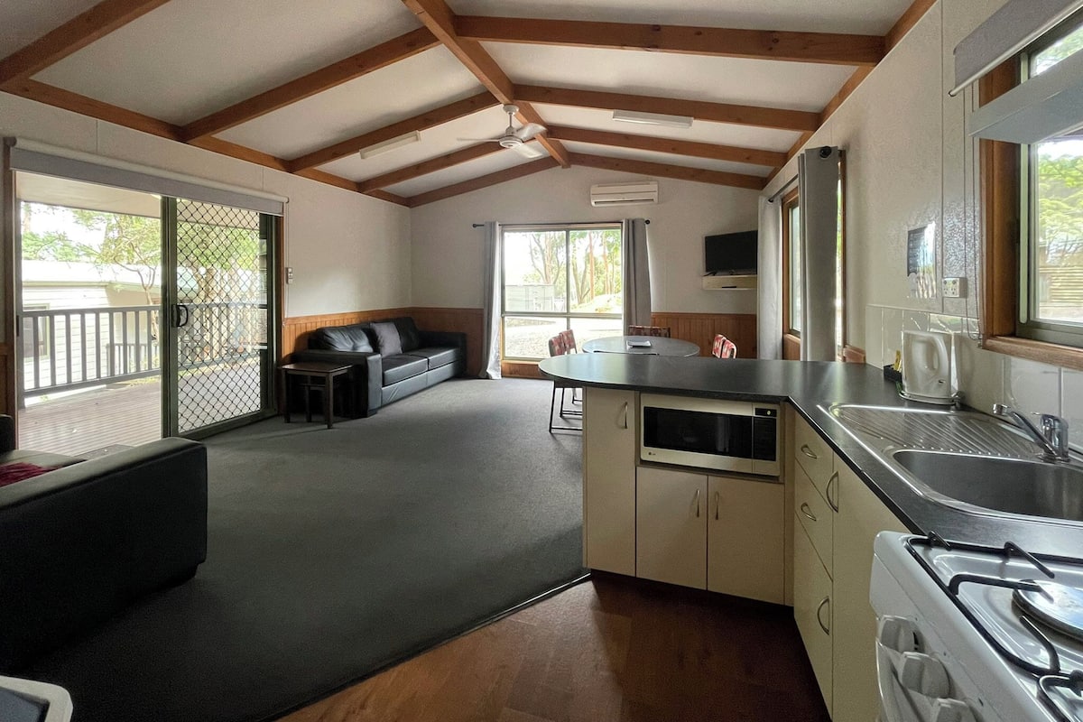 A compact kitchen with a stove, sink, and a dining area with a table and chairs.
