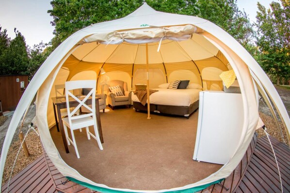 Relax in a dome-shaped retreat with a comfortable bed, table, and chair.