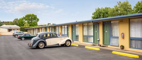 Een rij motelkamers met een klassieke auto ervoor geparkeerd.