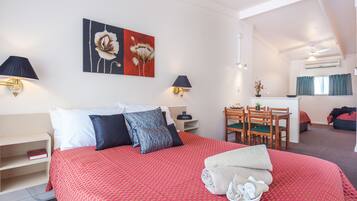 Una habitación de hotel con una cama grande, un escritorio y un comedor.