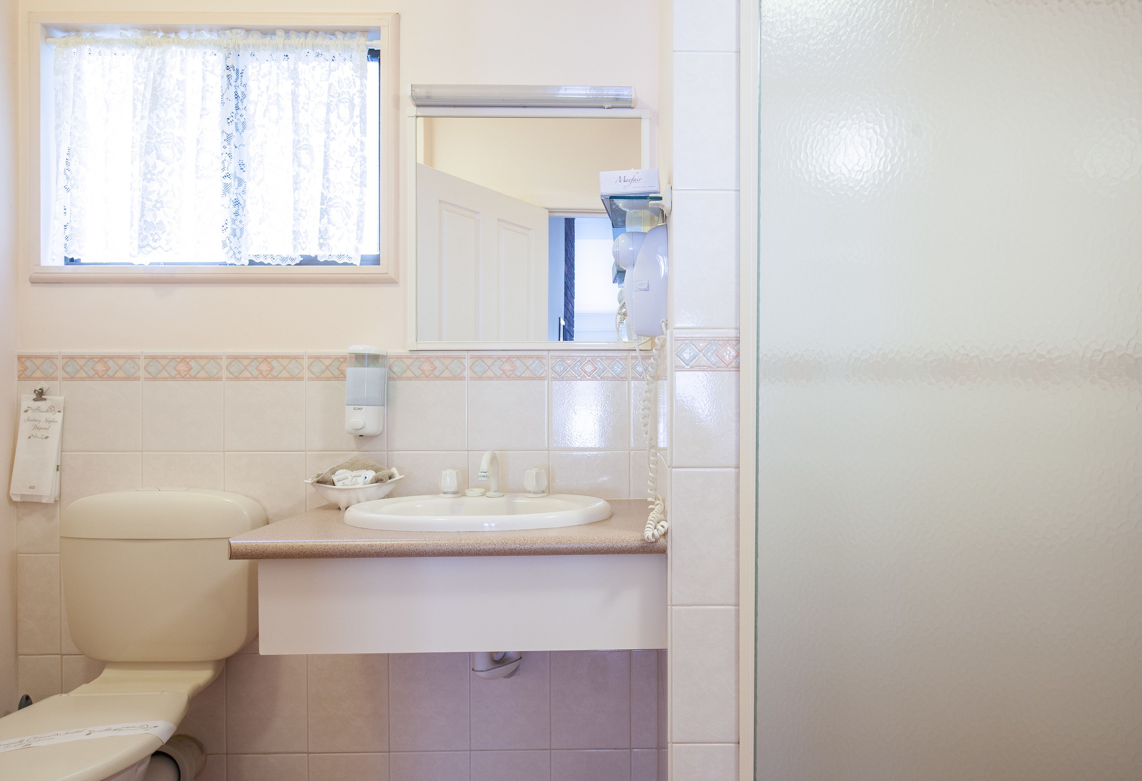Un baño con inodoro, lavamanos y espejo sobre él.