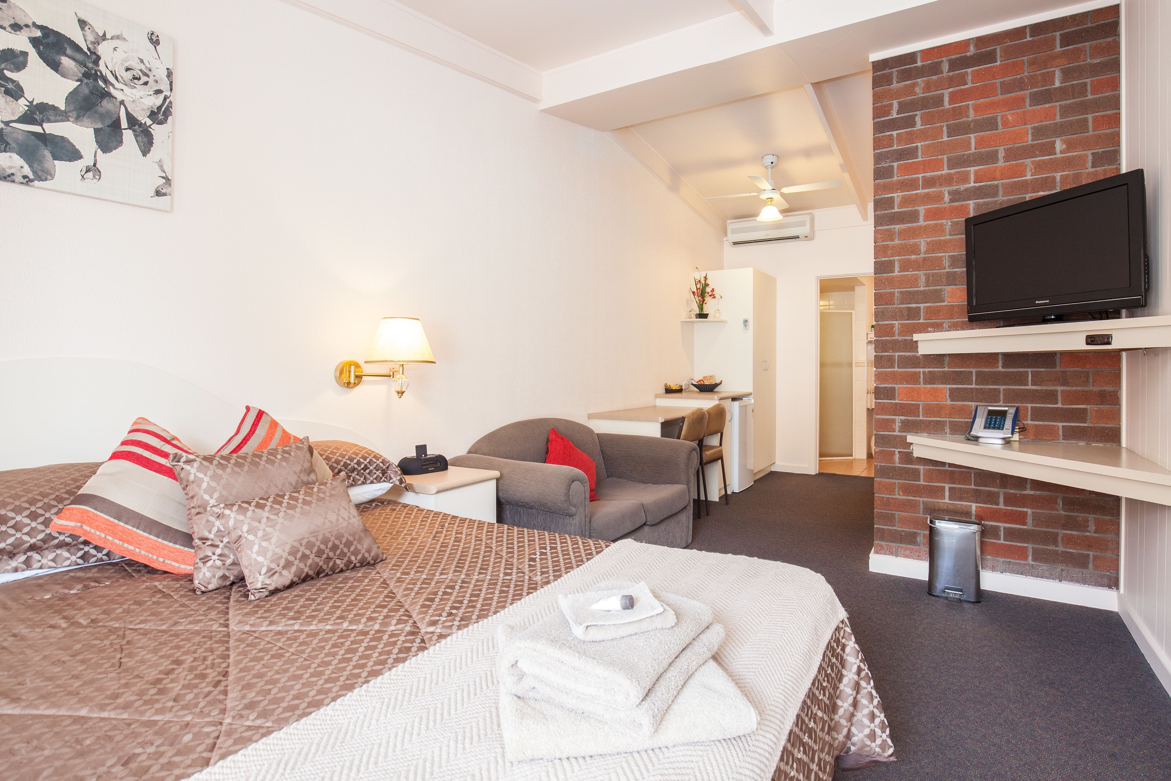 Une chambre d’hôtel équipée d’un lit, d’un bureau, d’une chaise, d’une télévision et d’une poubelle.
