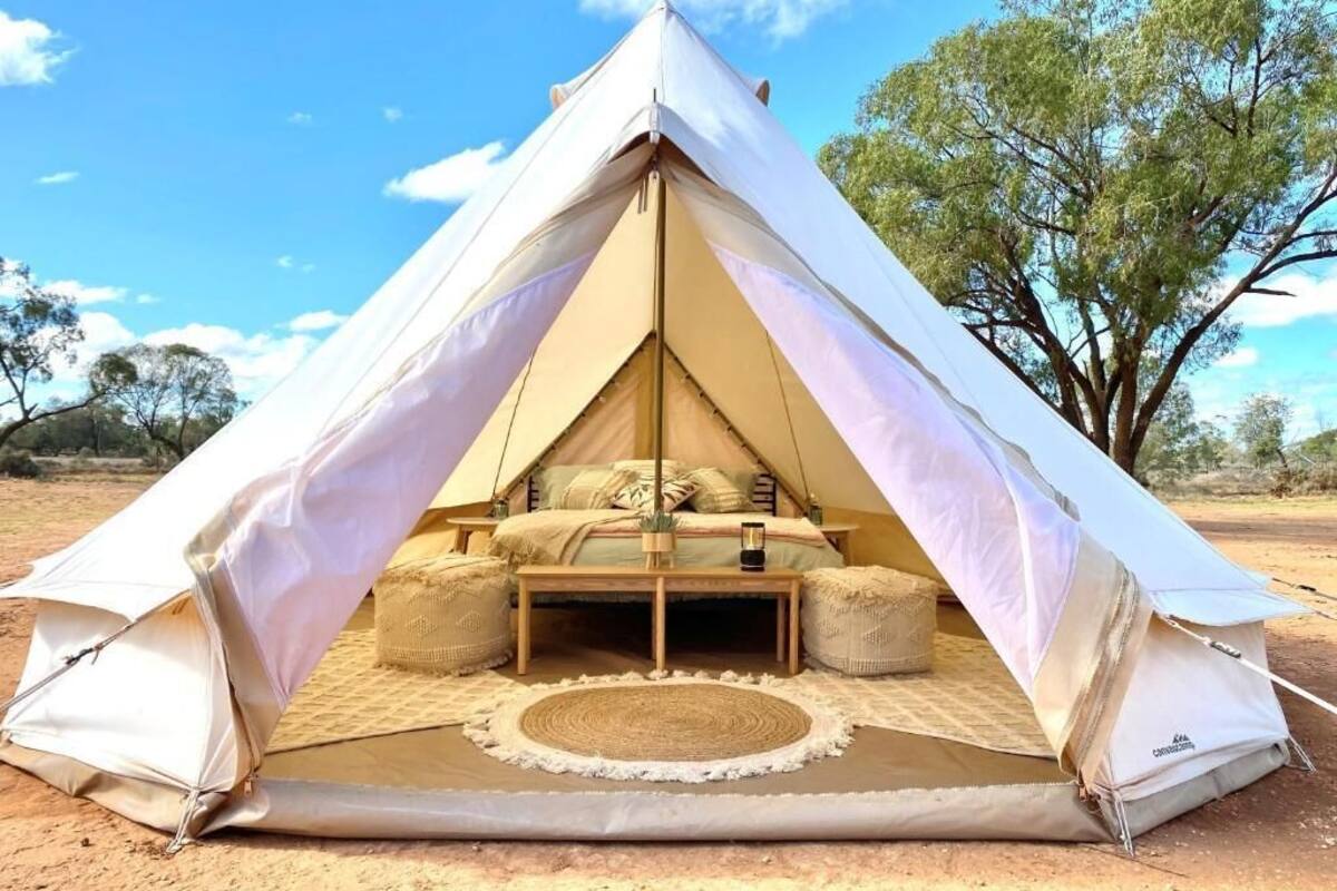 A tent with a bed, pillows, and a small table.