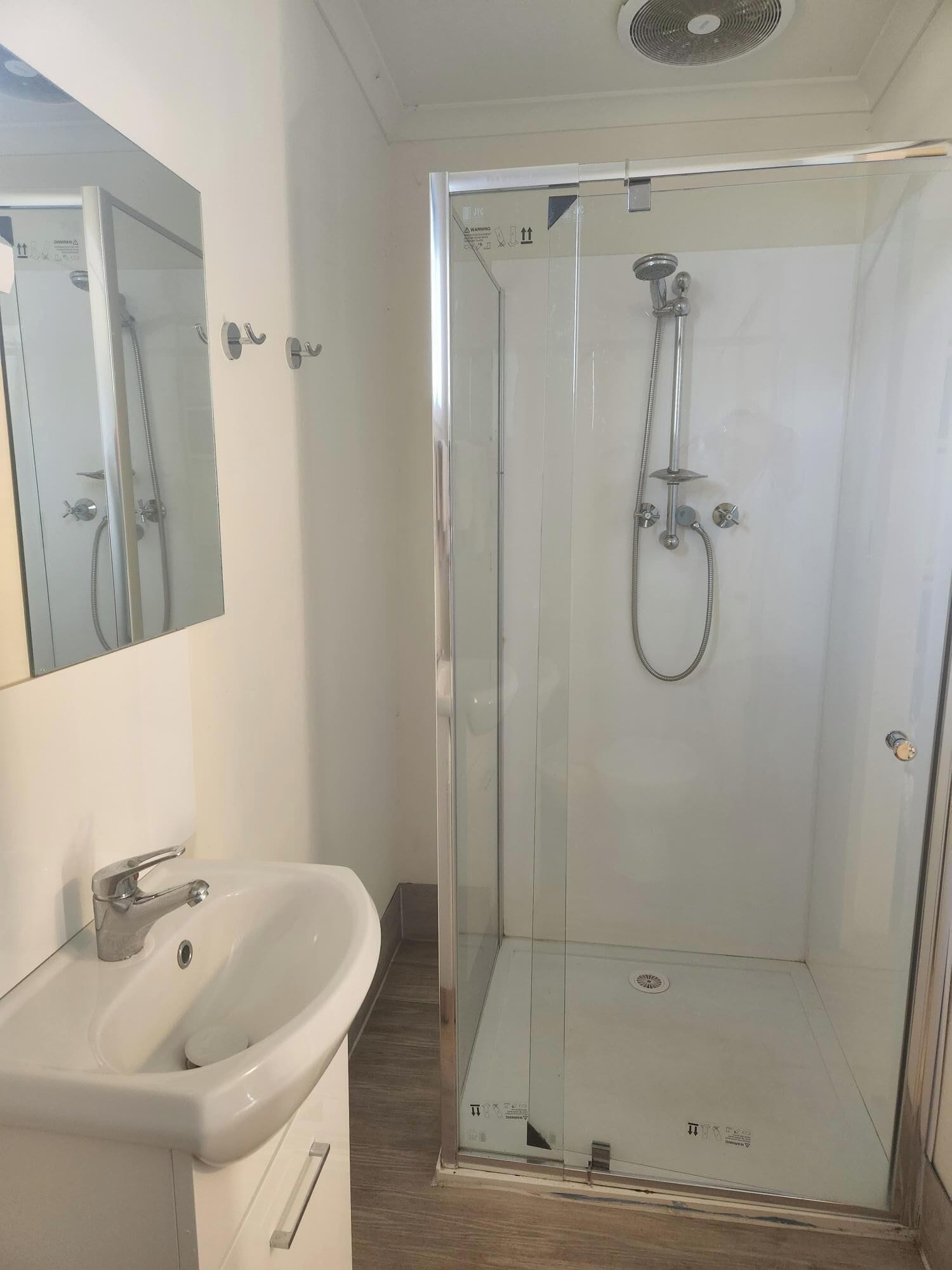 A modern bathroom with a glass-enclosed shower, a white sink, and a mirror.
