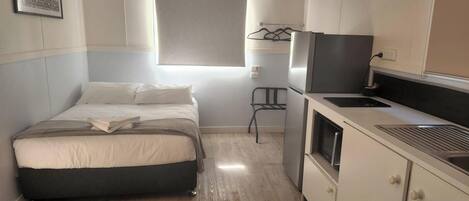Habitación pequeña con cama, kitchenette y ventana.