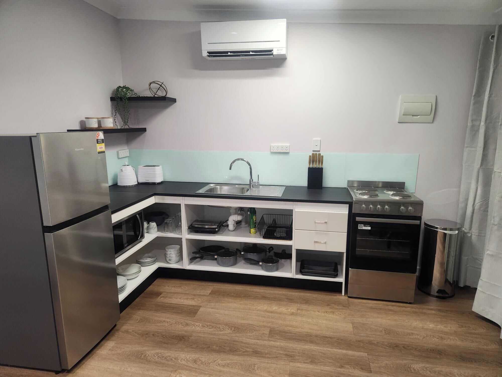 Une cuisine compacte équipée d’un réfrigérateur, d’une cuisinière, d’un évier et d’un four à micro-ondes.