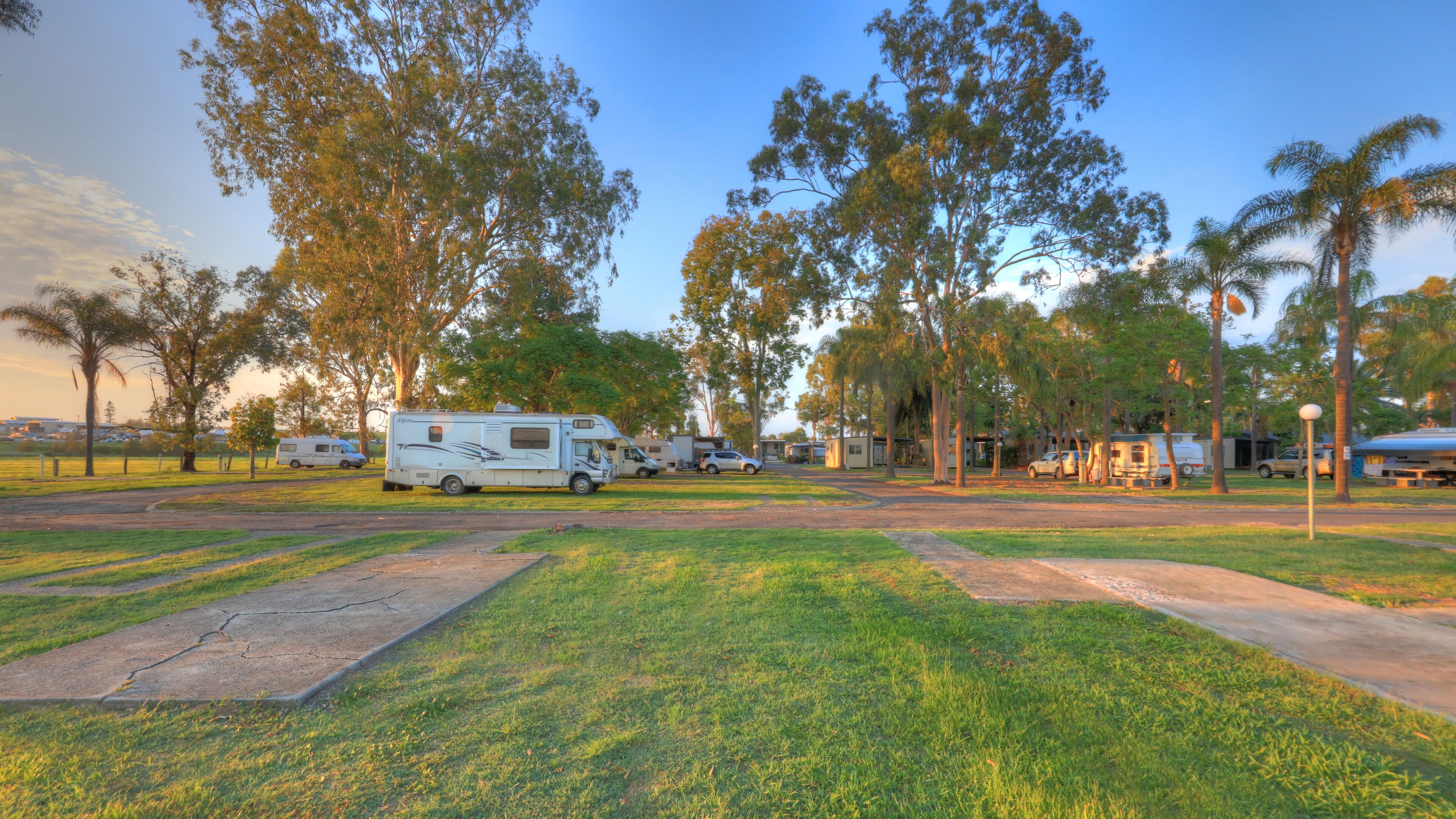 A campground with RVs, grassy areas, and trees.