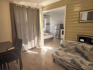 A compact living space with a bed, a sofa, a desk, and a kitchenette. - Glenwood Tourist Park & Motel (South Grafton)