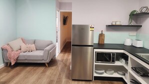 A compact kitchen with a stainless steel refrigerator, a microwave, and a toaster on the counter. - Glenwood Tourist Park & Motel (South Grafton)