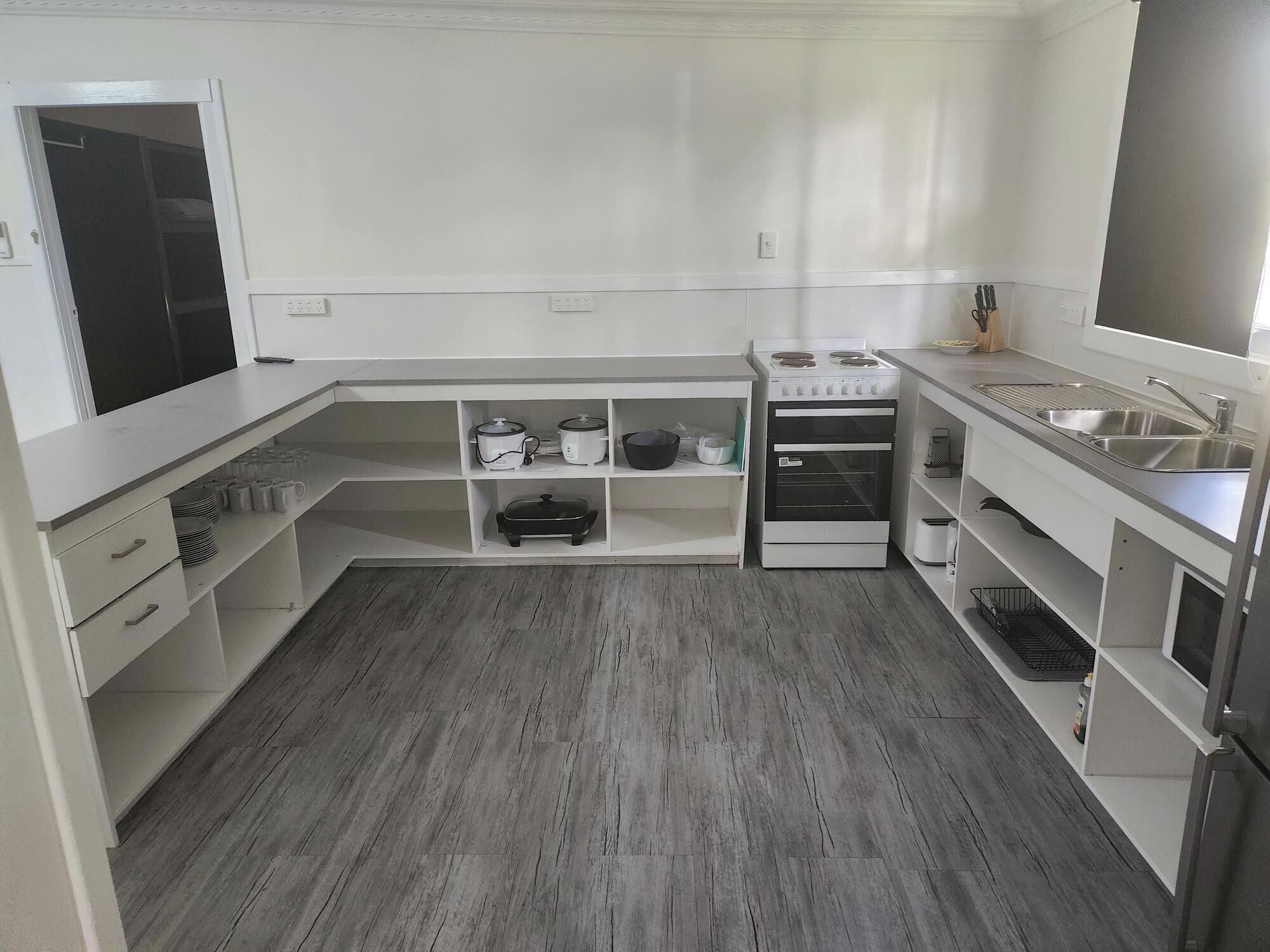 Una cocina moderna con armarios blancos, horno integrado y pileta de acero inoxidable.