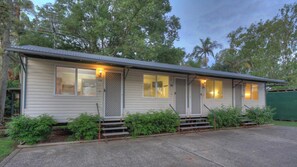 A single-story mobile home with numbered windows, a porch, and a green fence in the background. - Glenwood Tourist Park & Motel (South Grafton)