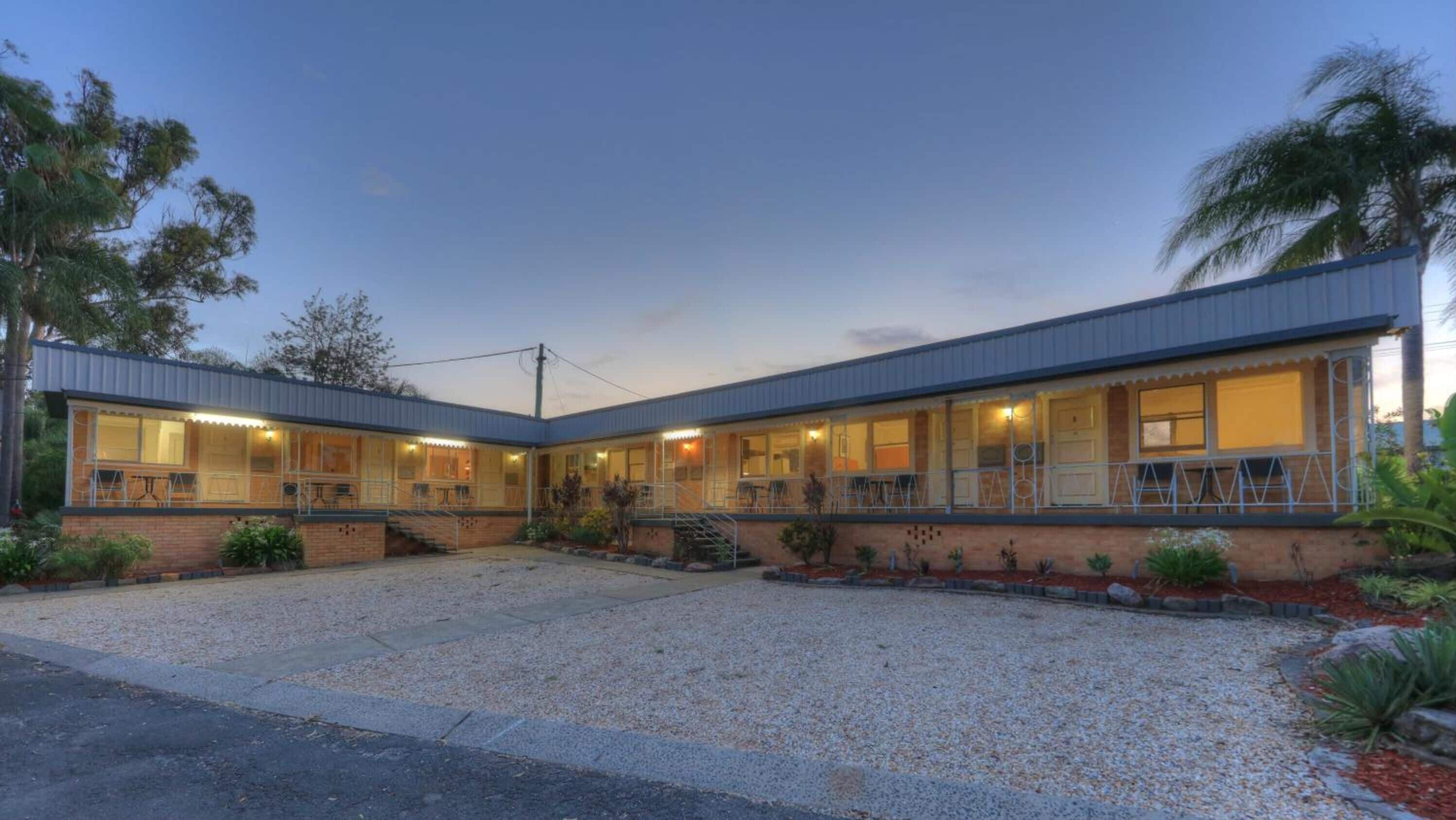 A two-story motel with a covered patio and a gravel driveway.