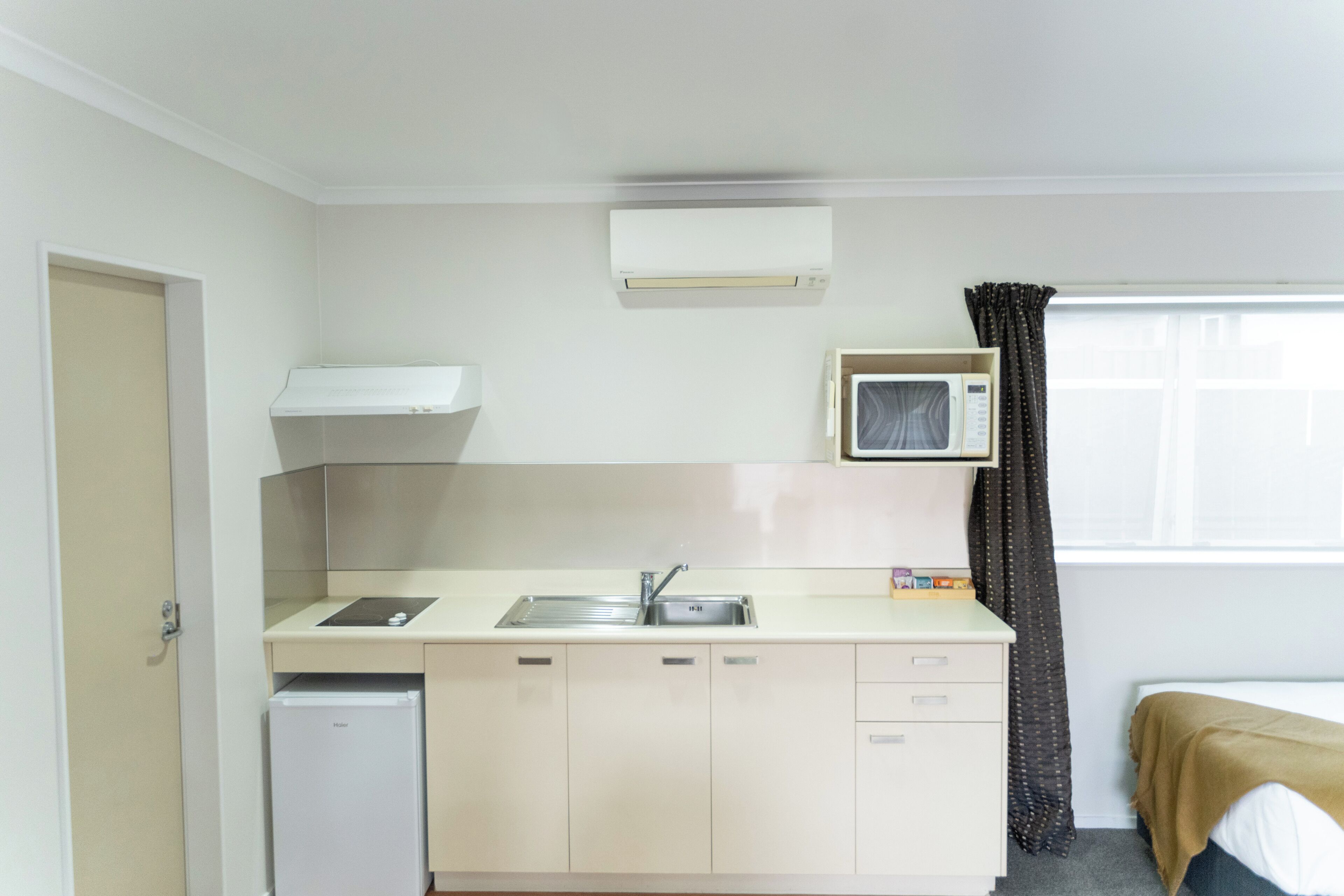 Una cocina compacta con un lavamanos, un microondas y un refrigerador.