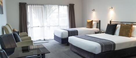Habitación de hotel con dos camas, un escritorio y una silla.
