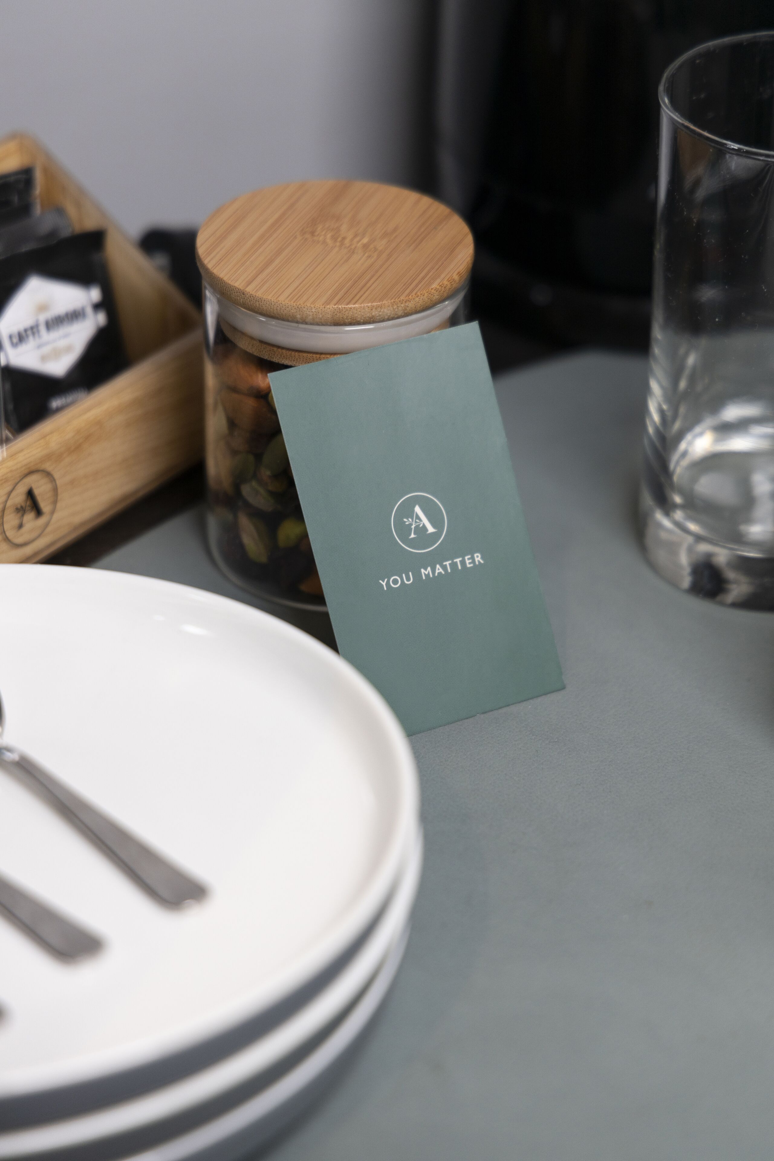 A table with a card reading "YOU MATTER," a jar with coffee beans, and a glass of water.