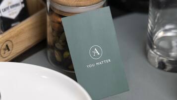 A table with a card reading "YOU MATTER," a jar with coffee beans, and a glass of water.