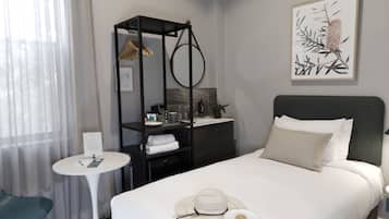 Habitación de hotel ordenada con una cama, una mesita redonda pequeña, una silla, un armario y una obra de arte enmarcada en la pared.