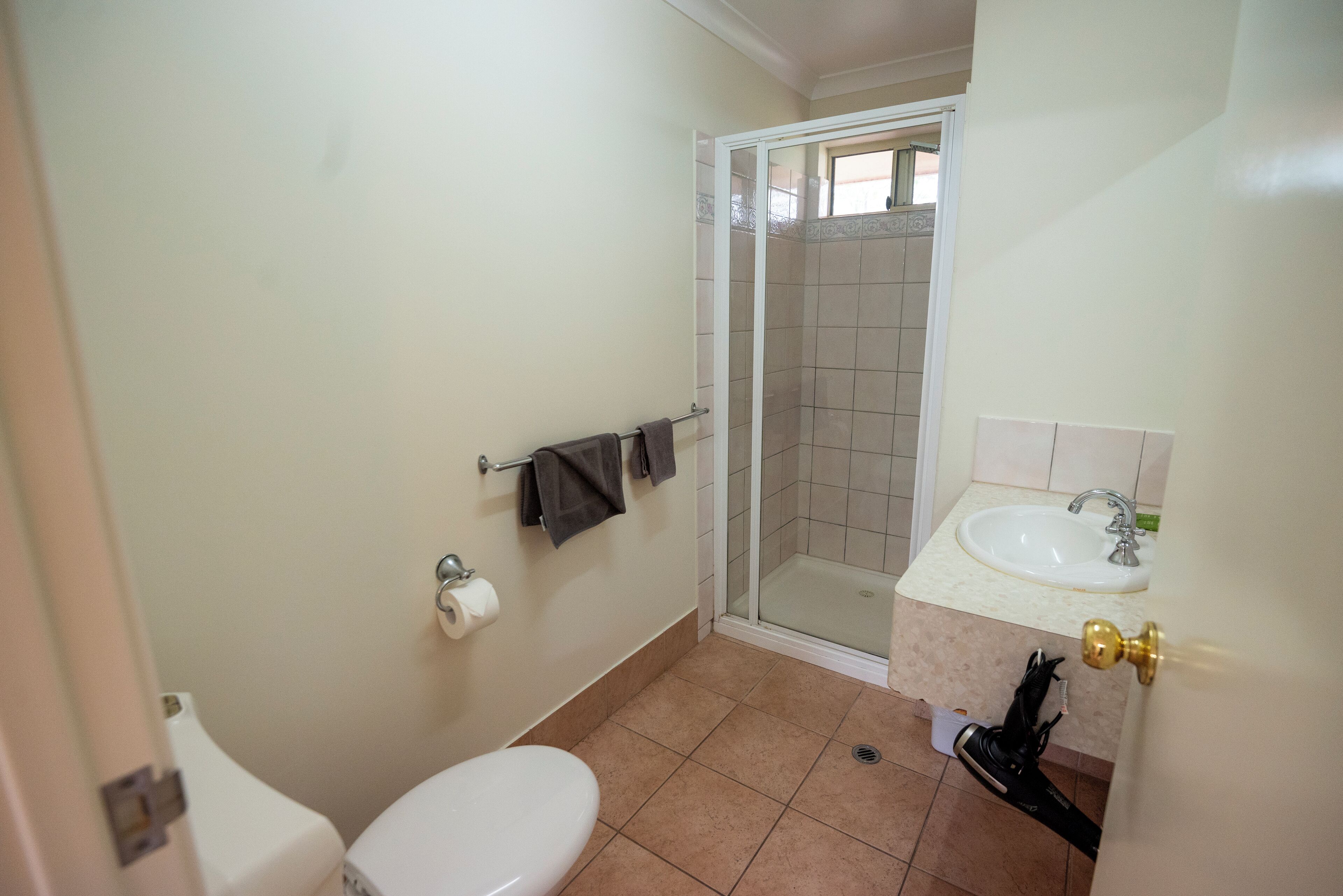 Een badkamer met toilet, wastafel, douche en een handdoekrek.
