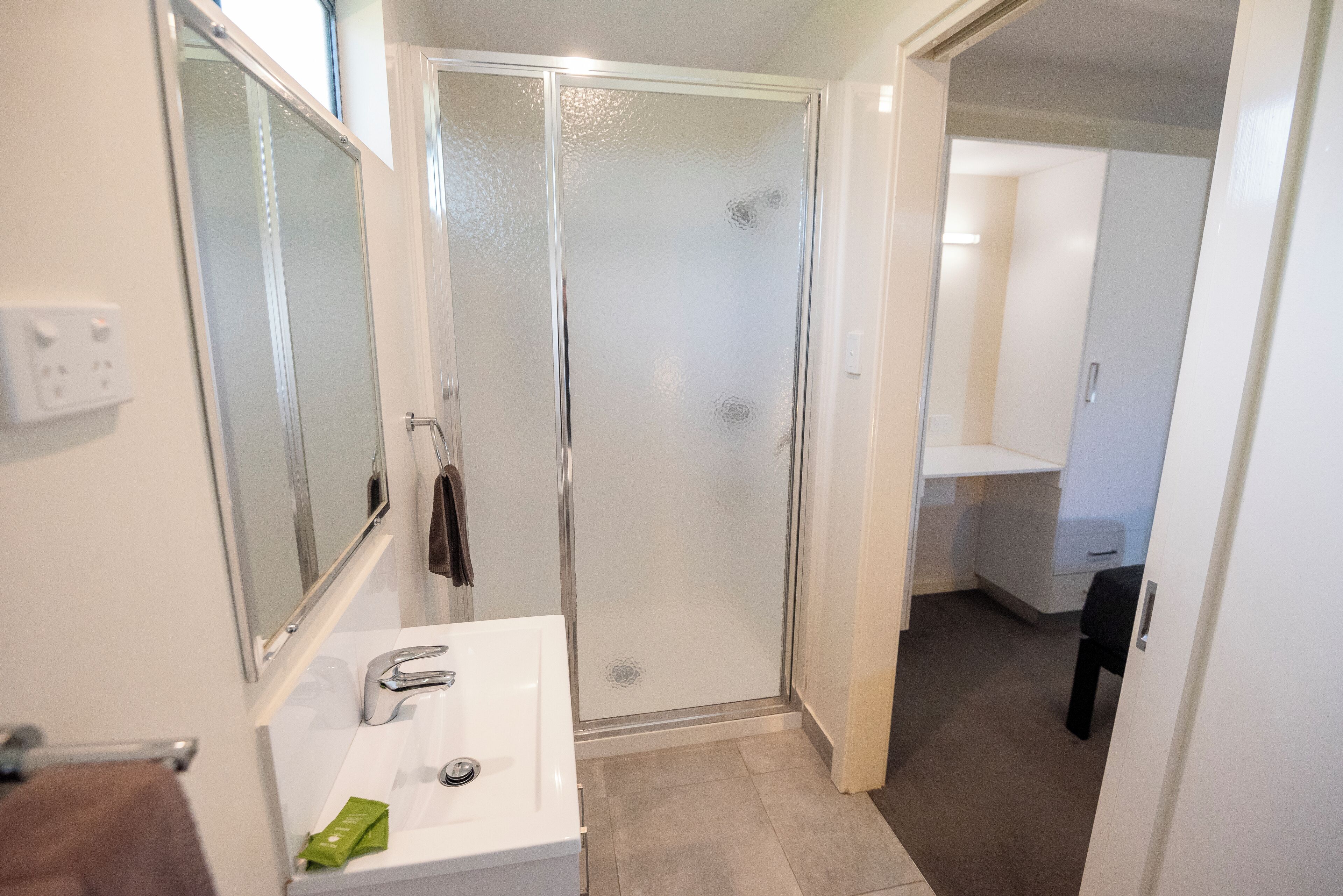 A modern bathroom with a glass-enclosed shower, a white sink, and a mirror.