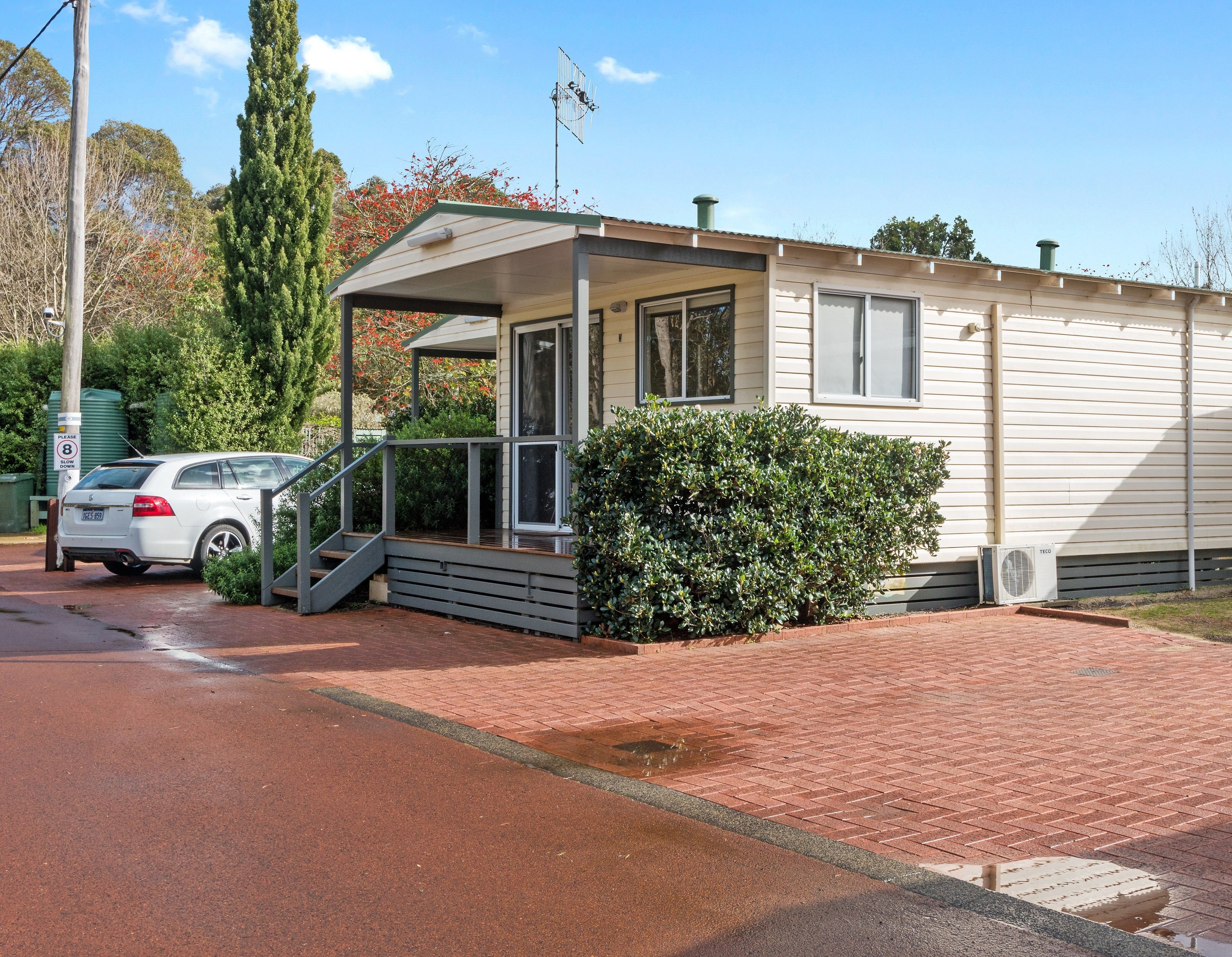 A single-story mobile home with a covered porch and a small front yard.