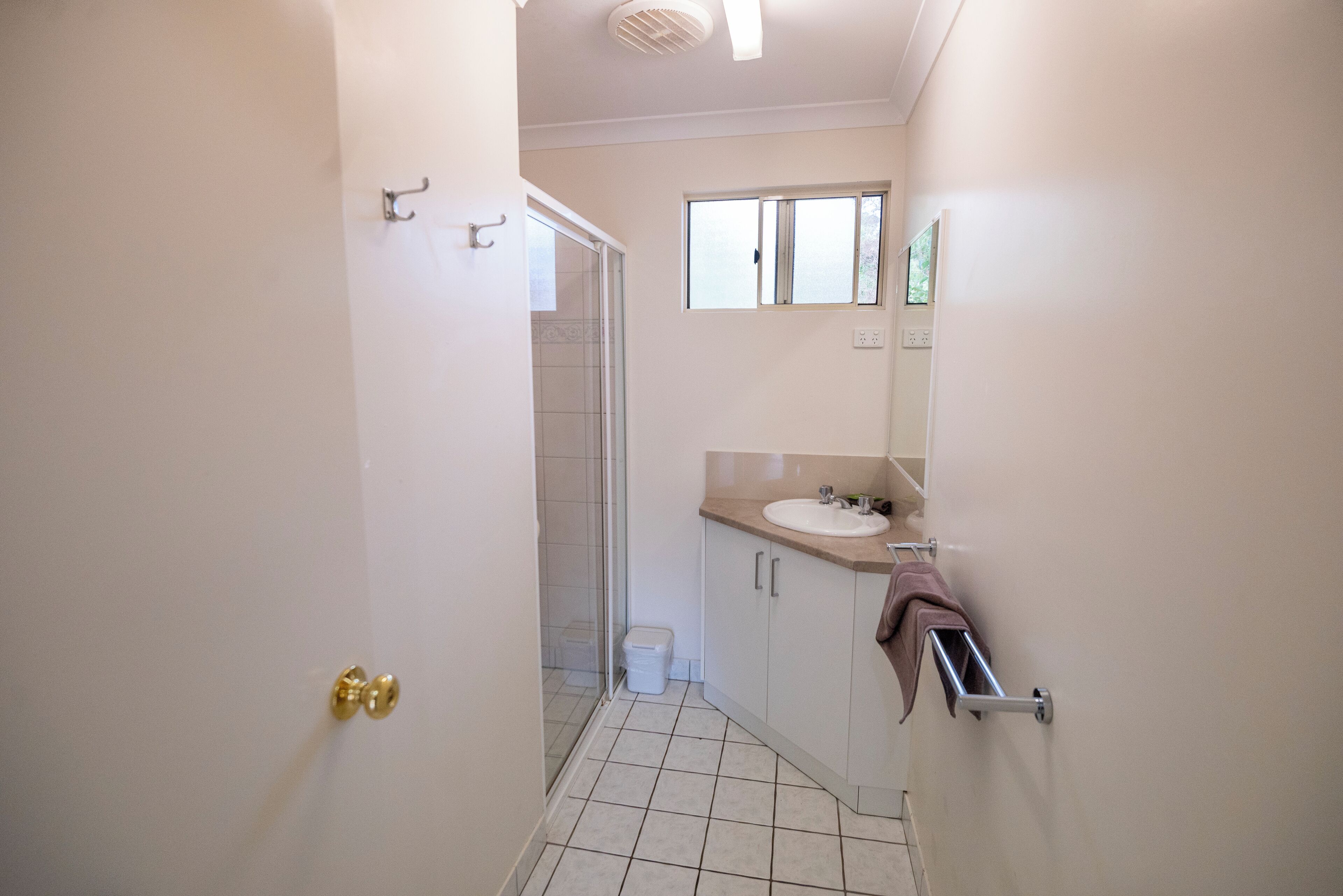 A narrow bathroom with a toilet, sink, and mirror.