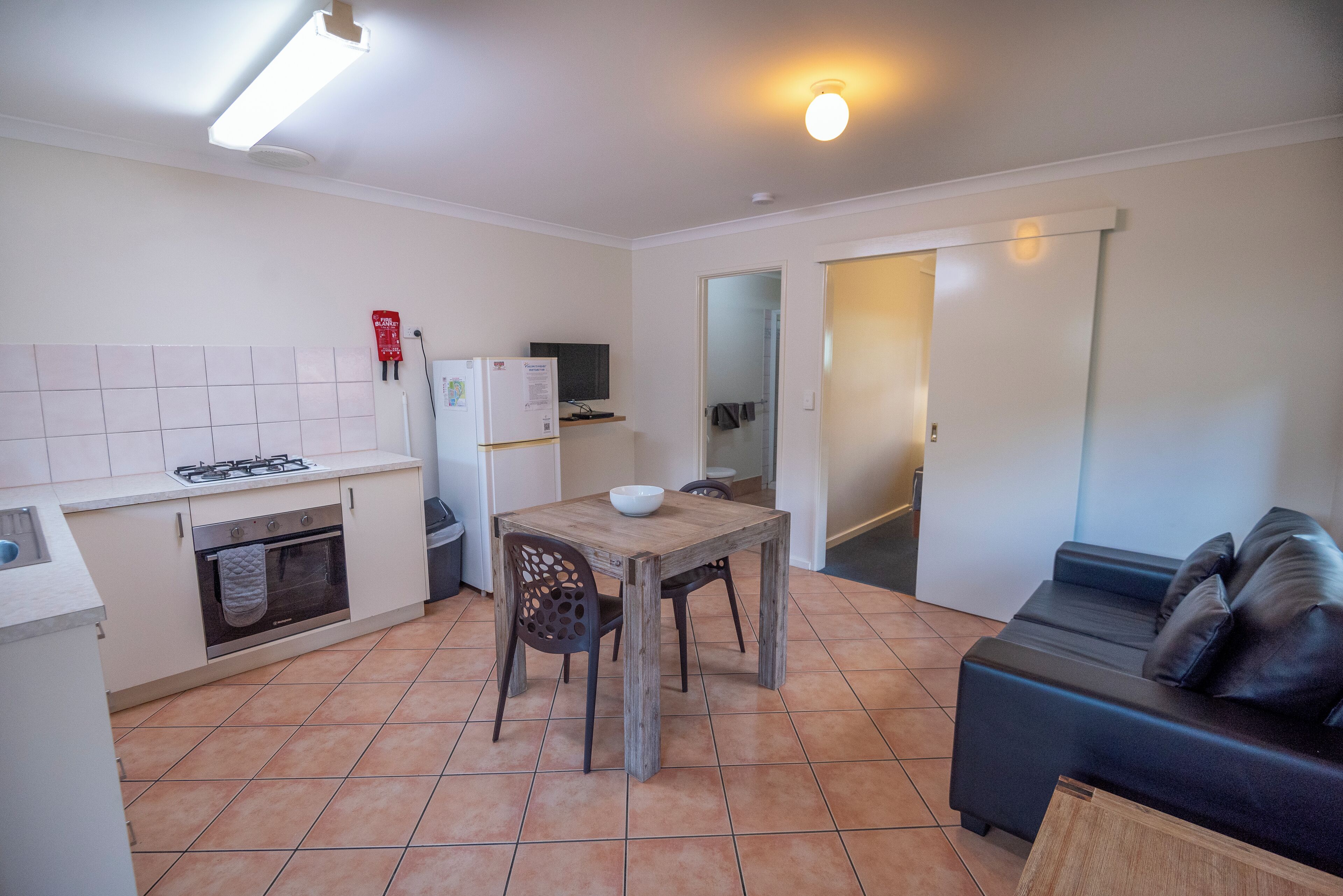 Une cuisine de taille réduite comprenant une table à manger, des chaises, un canapé et un téléviseur.