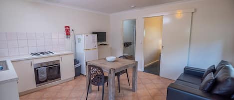 Une cuisine de taille réduite comprenant une table à manger, des chaises, un canapé et un téléviseur.