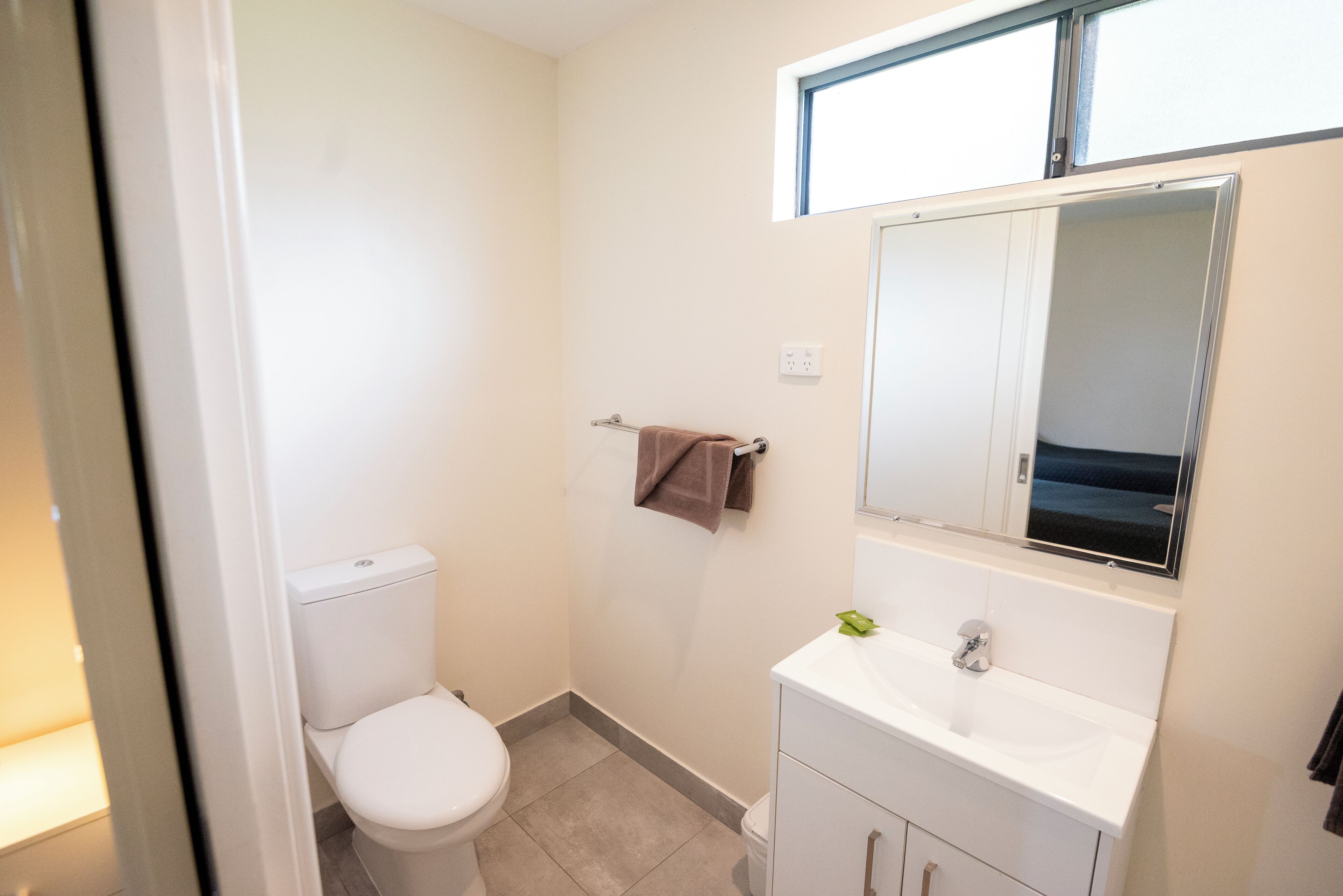 A small, clean bathroom with a white toilet, a sink, and a mirror.