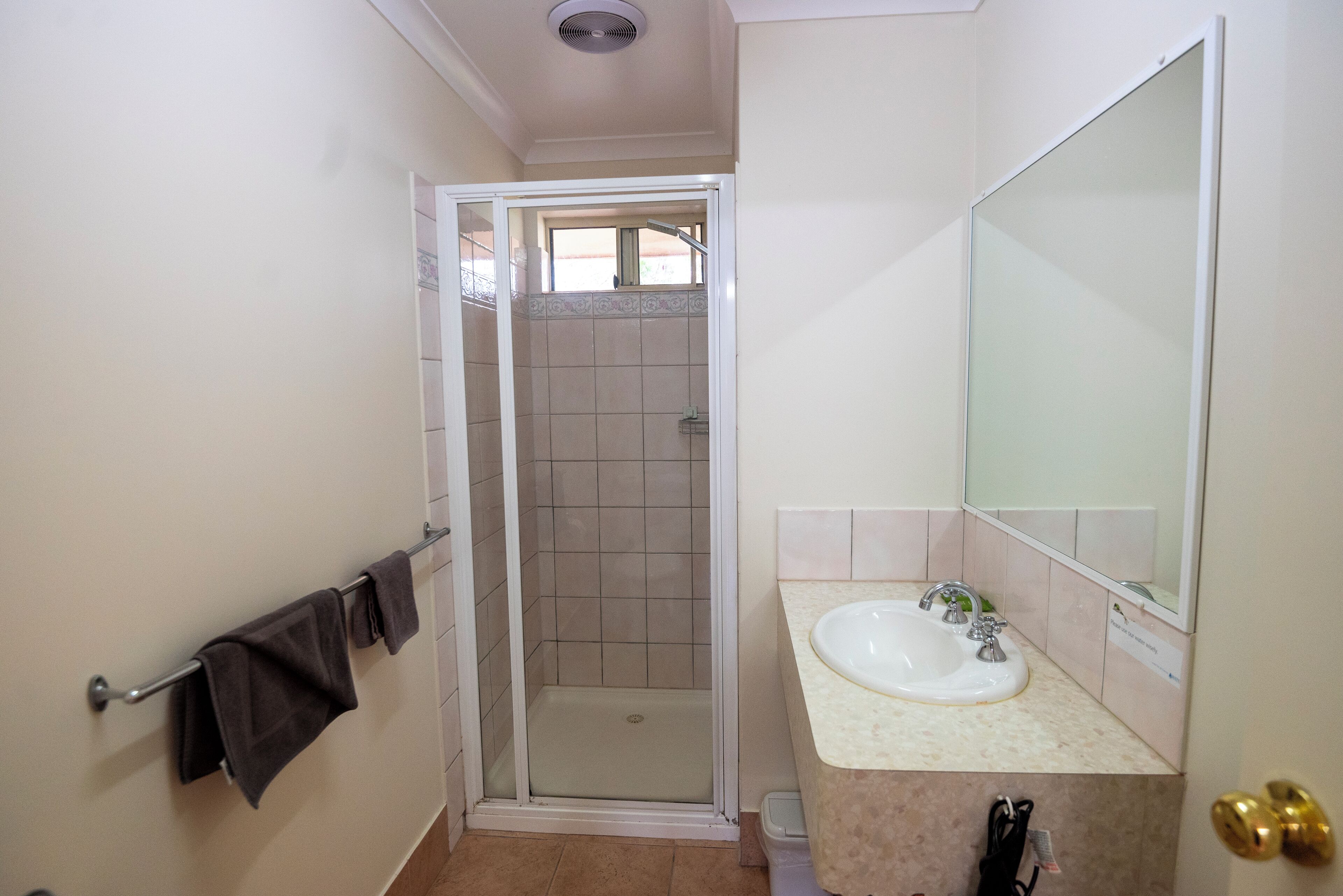 A bathroom with a shower, sink, and towel rack.
