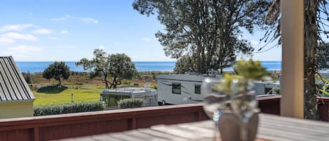 A balcony with a view of the sea, a glass of water, and a small table.