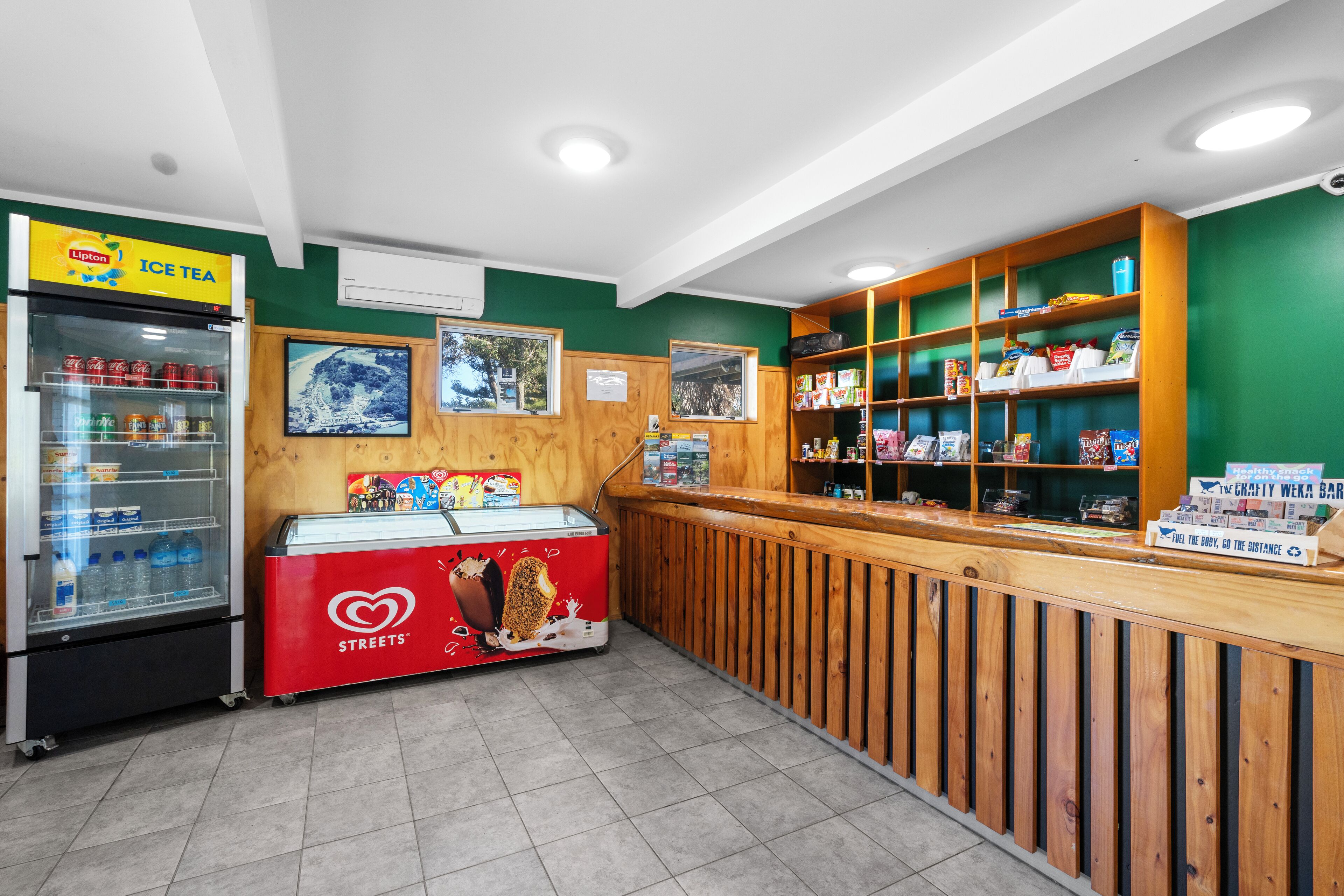 A food service area with a refrigerated drink cooler, a freezer, and a counter with a sign for 'Ice Tea'.