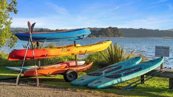 A row of kayaks and paddleboards by a lakeside.
