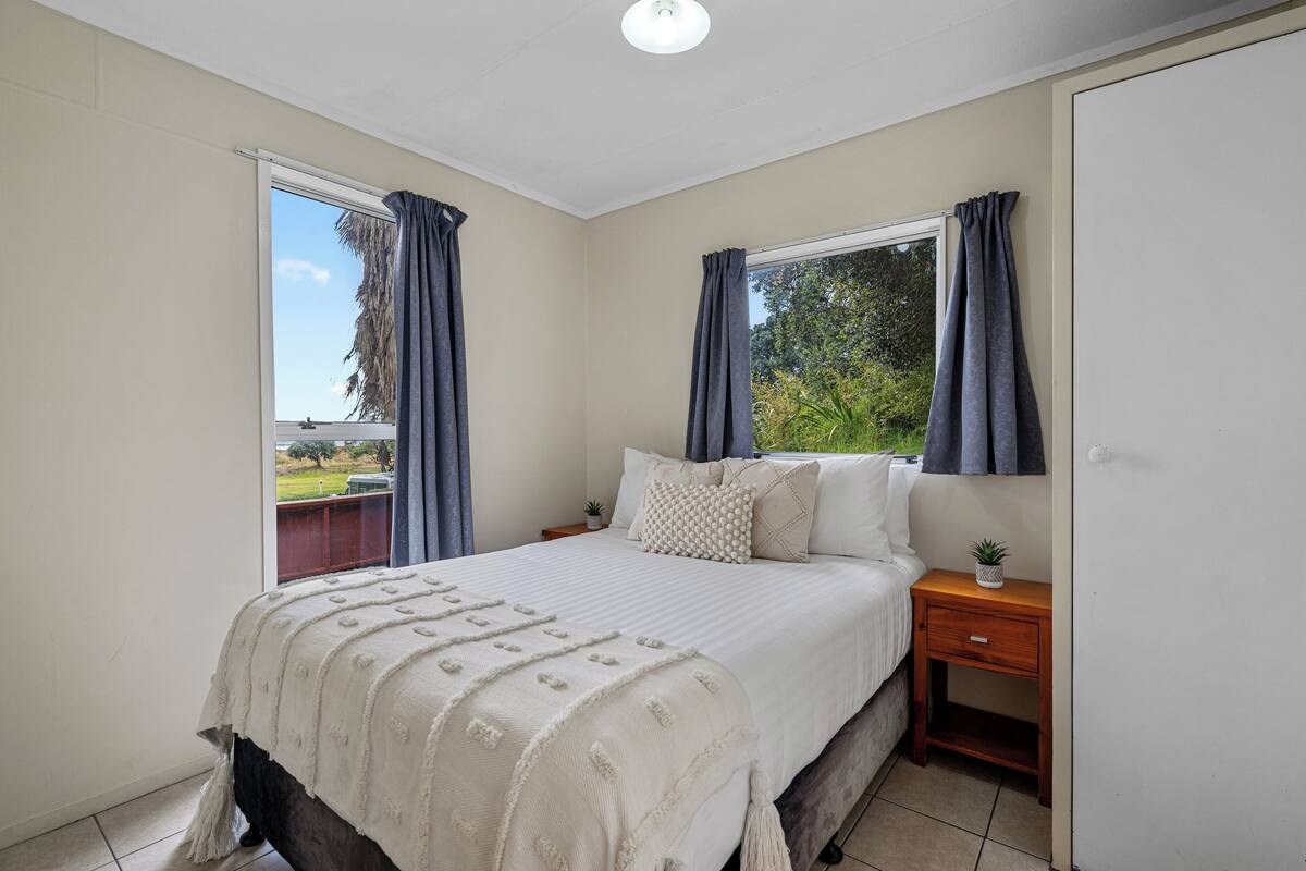 Een slaapkamer met een bed, nachtkastjes en uitzicht op de omgeving.