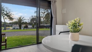 Une pièce avec une grande fenêtre, une plante en pot sur une table et une chaise.