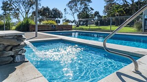 Une piscine avec un mur en pierre et une rambarde métallique.