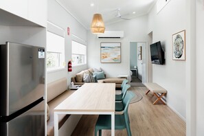 A modern kitchen with a built-in refrigerator, a wooden dining table, and teal chairs.