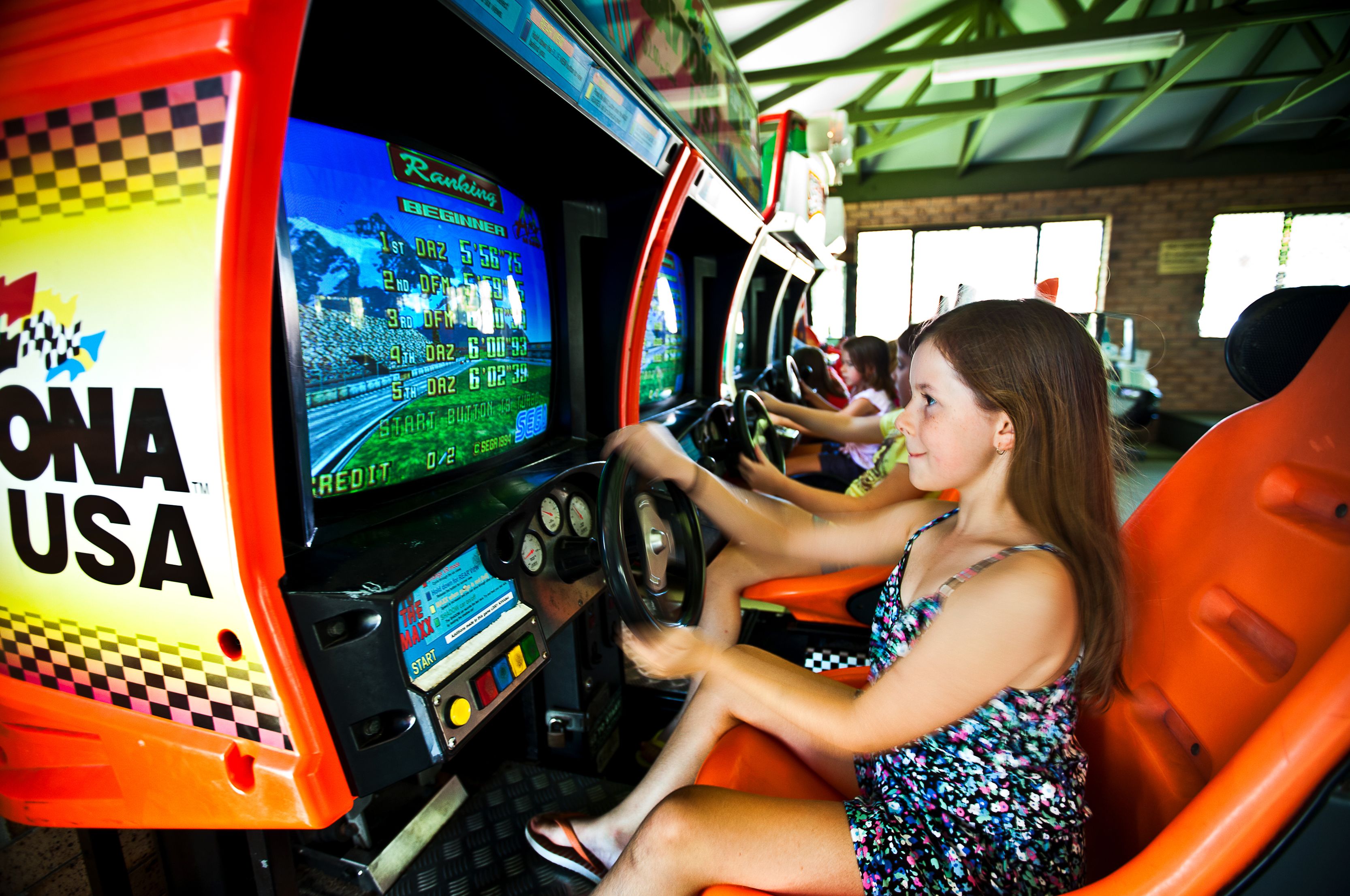 A woman driving a racing simulator with a digital display and steering wheel.