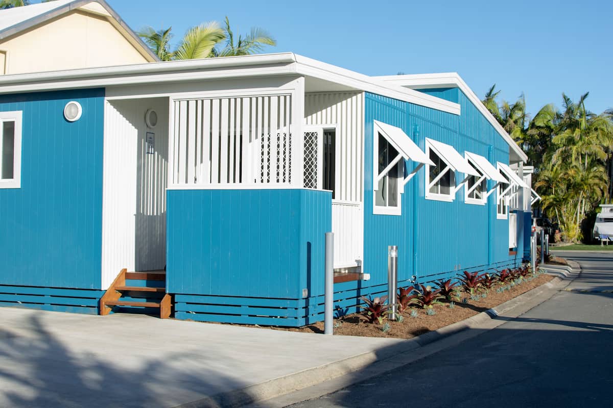 A blue building with white trim, a porch, and a small garden area.
