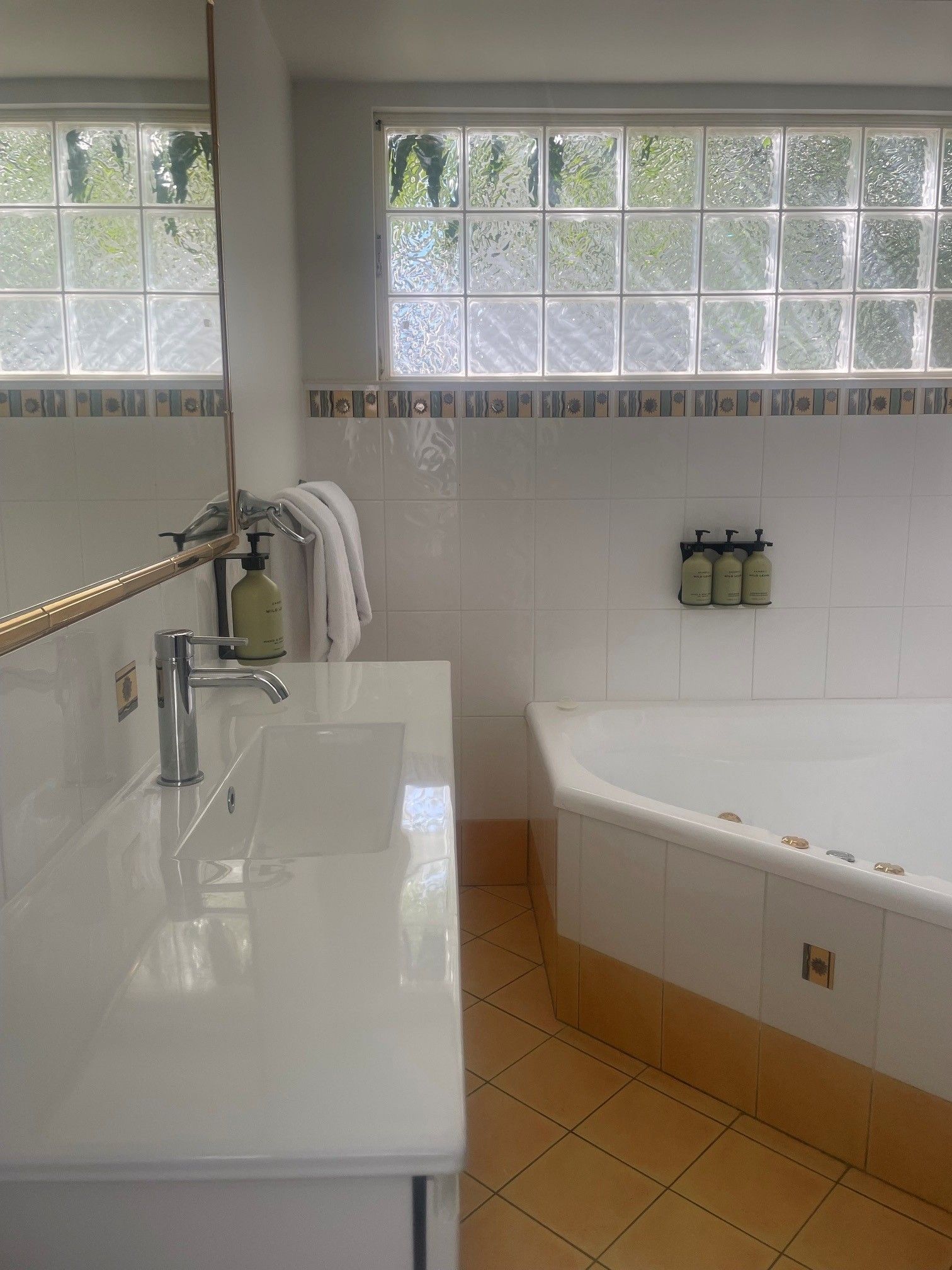 Une salle de bain avec un lavabo blanc, une baignoire et une fenêtre aux carreaux de verre dépoli.